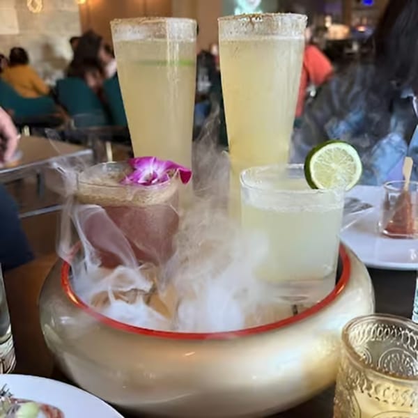 Four cocktails, two tall and two short, served in a smoky golden bowl at Artha Indian Bistro.
